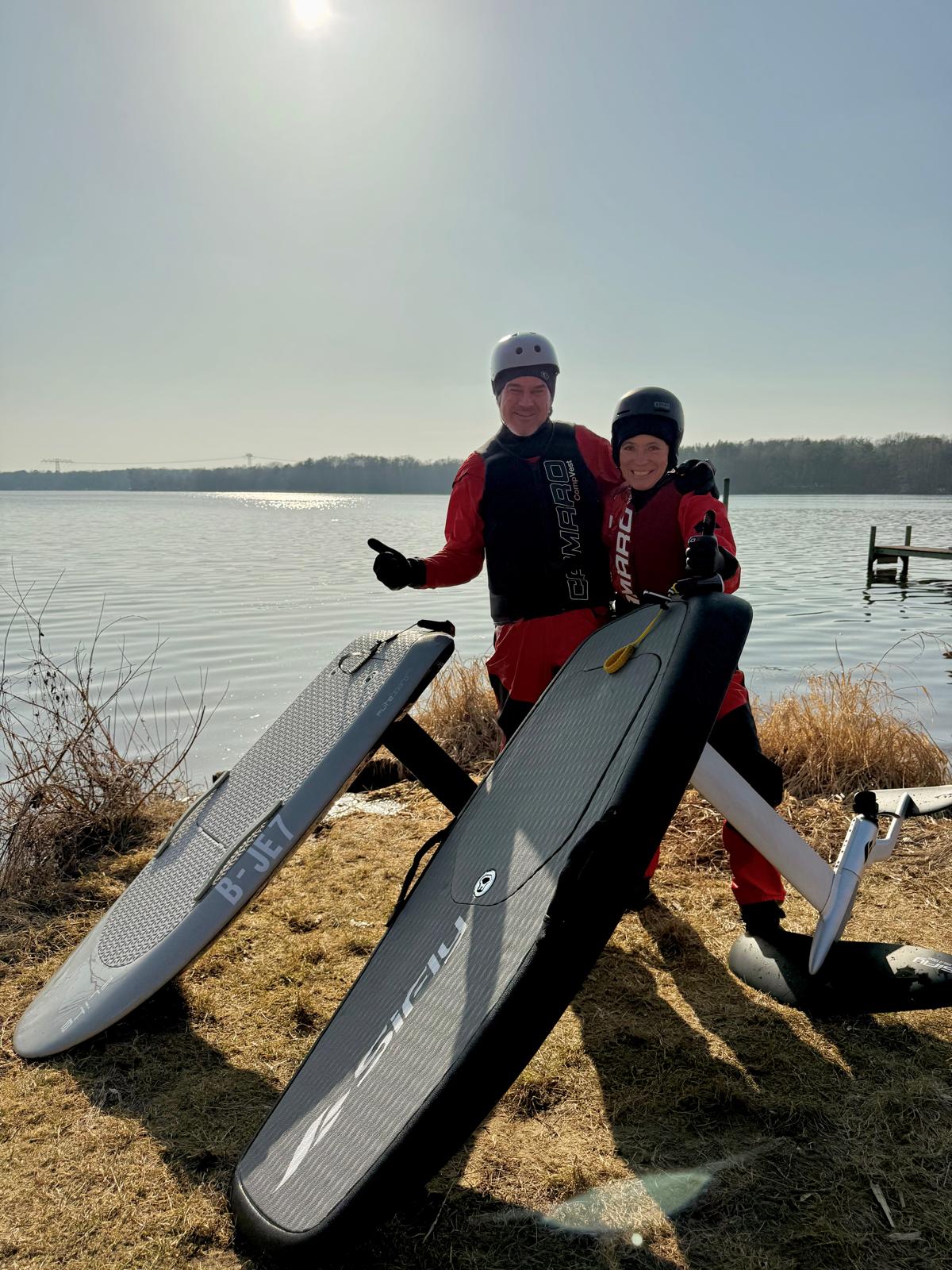 Paar mit E-Foil Boards am Seeufer